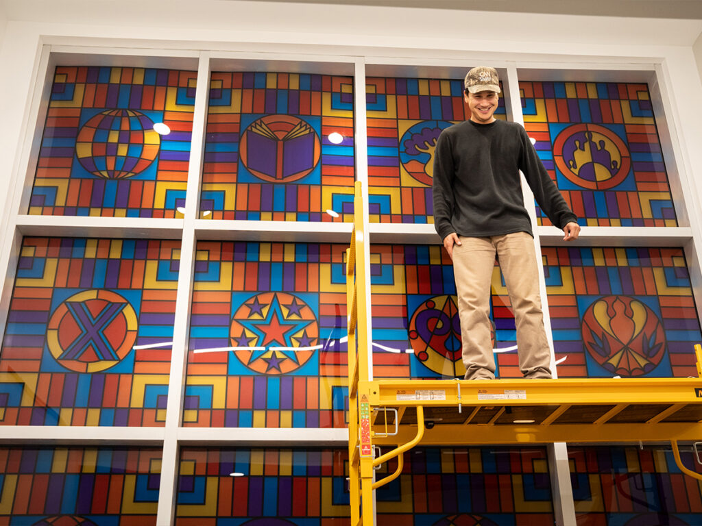Gabriel Eng-Goetz installs acrylic panels at the Stanford L. Warren Branch Library. Photo by Angelica Edwards.