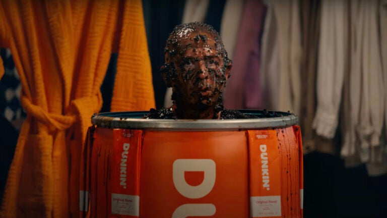 Jeremy Strong in an orange Dunkin' barrel covered in wet coffee grounds for the 2025 Dunkin' Super Bowl commercial.