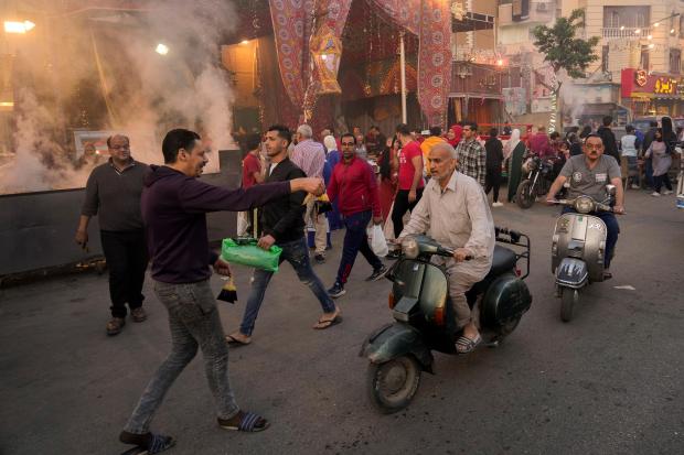 FILE – A volunteer distributes free juice ahead of Iftar,...