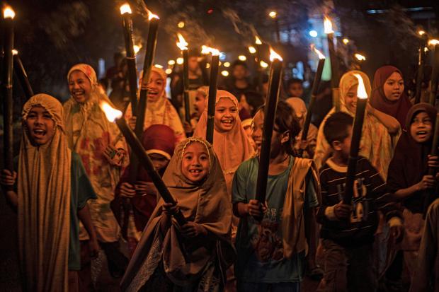 FILE – Muslim girls carry torches during a parade to...