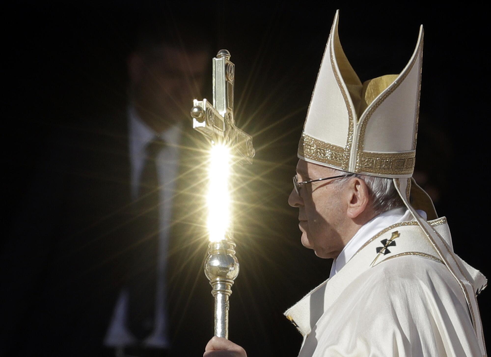 Pope Francis' pastoral staff is hit by a ray of the sun as he carries it outdoors.