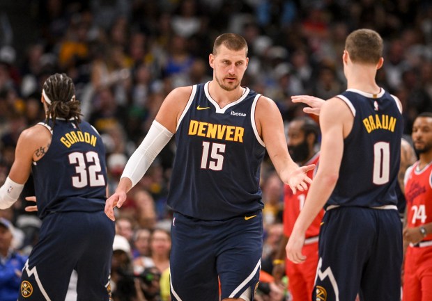 Nikola Jokic (15) of the Denver Nuggets low fives Christian...