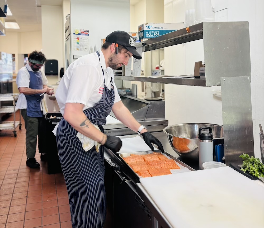 Isaiah Jernigan preps salmon as Shane Jernigan peels potatoes. Photo by Ava Epstein — The 9th Street Journal