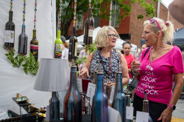Marty Rogers, left, and Amy Slagle look over the hanging wine bottle planters at vendor Where The Art Is by Hildy at the Westminster Wine Stroll on Main Street. (Karen Jackson/Freelance)