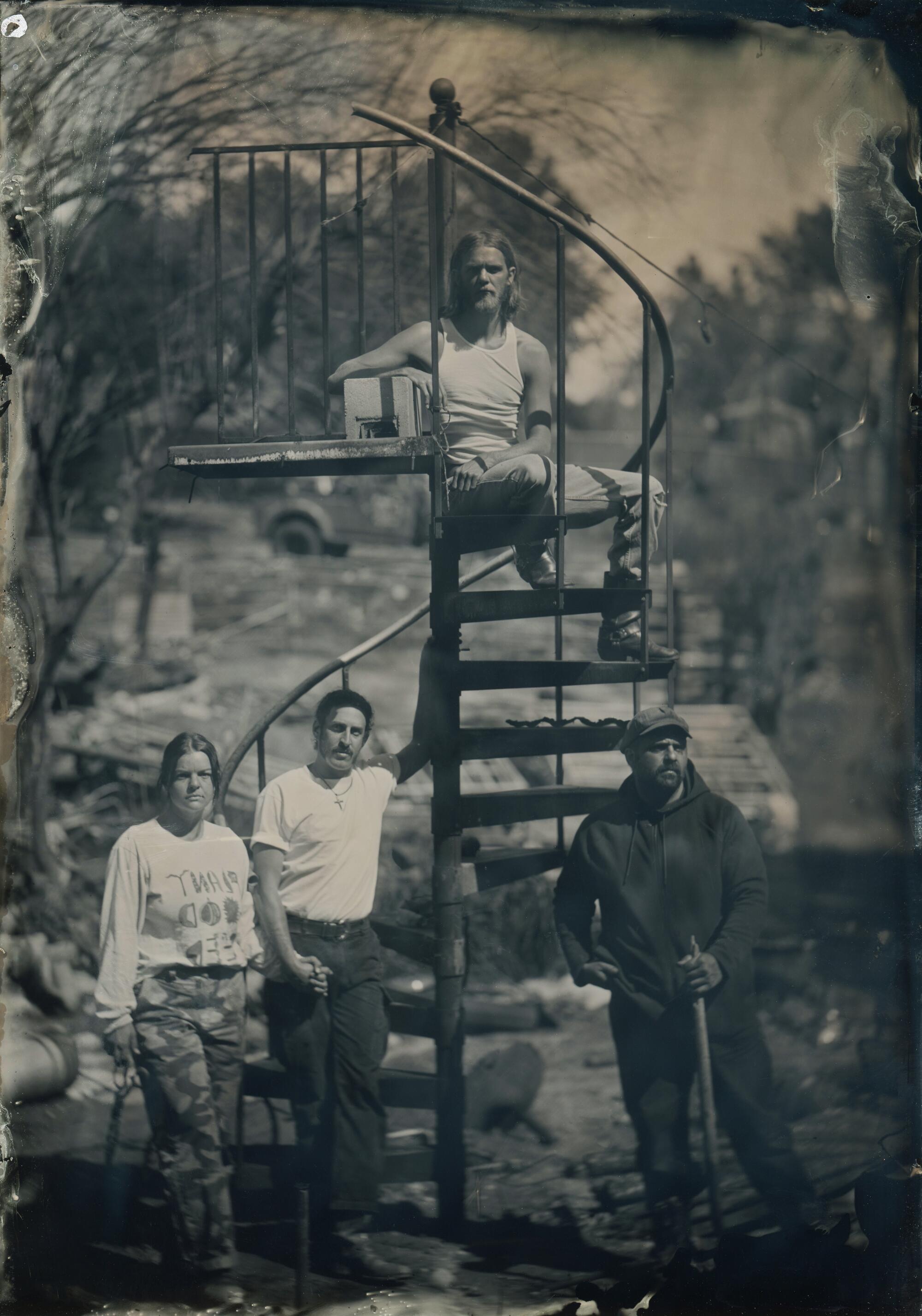 Artists stand around a metal spiral staircase in the rubble of Zorthian Ranch.