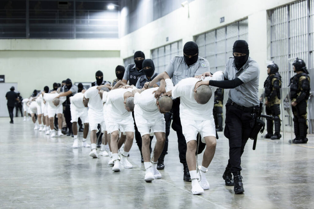 In this photo provided by El Salvador's presidential press office, prison guards transfer depor ...