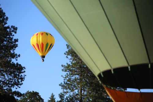 A yellow balloon floats in the sky by some trees