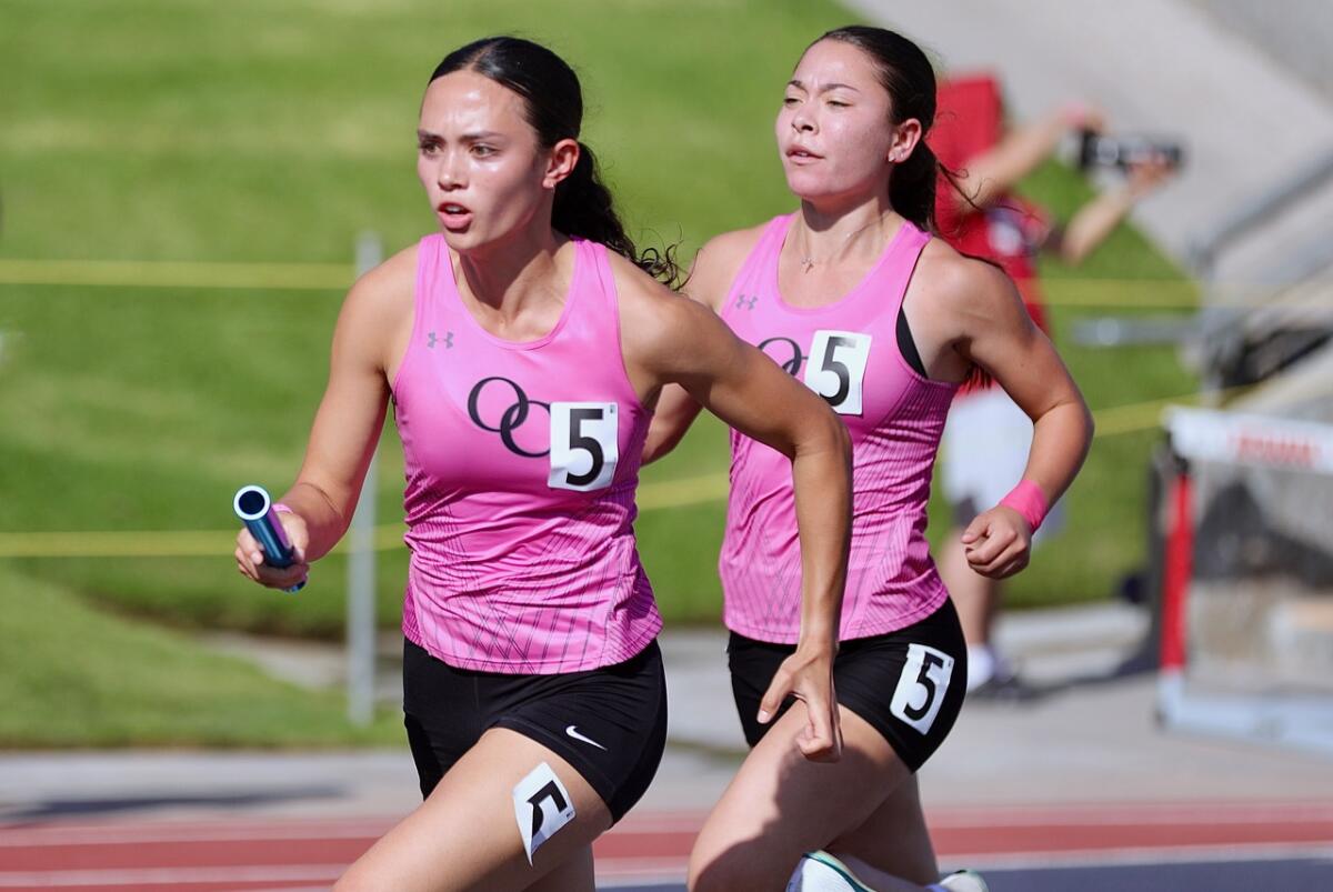 Kyra Terry, left, receives the baton from Oaks Christian teammate Rayah Rodriguez.