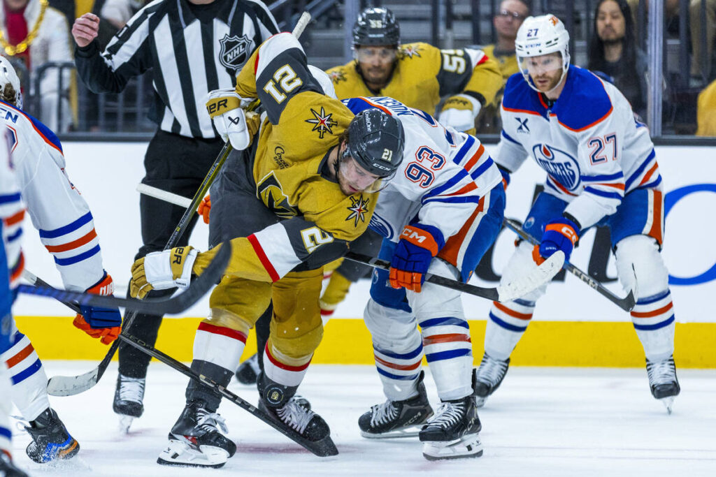 Golden Knights center Brett Howden (21) deflects a puck off his skate as he faces off with Edmo ...