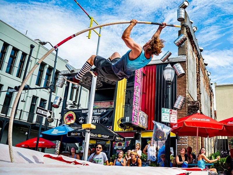 A pole vaulter launches into the air in downtown Mobile during the 2024 Dauphin Street Vault event.