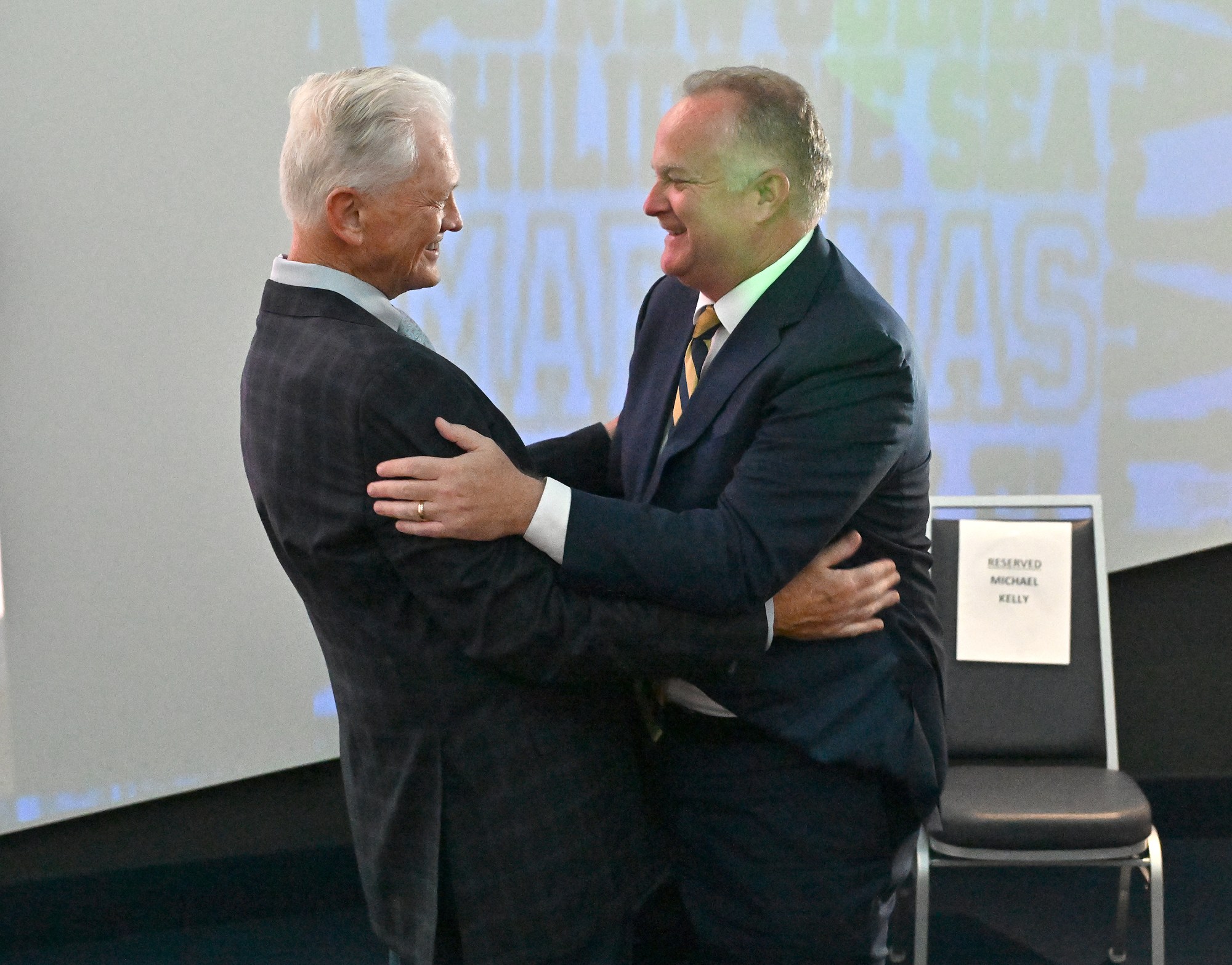 Outgoing Navy Athletic Director Chet Gladchuk, left, gives new AD Michael Kelly a warm welcome. Outgoing Navy Athletic Director Chet Gladchuk said his goodbyes to staff today and introduced new Navy athletic director Michael Kelly during an event at academy. (Paul W. Gillespie/Staff)
