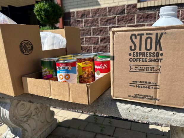Cans and boxes of food sit on a bench outside...
