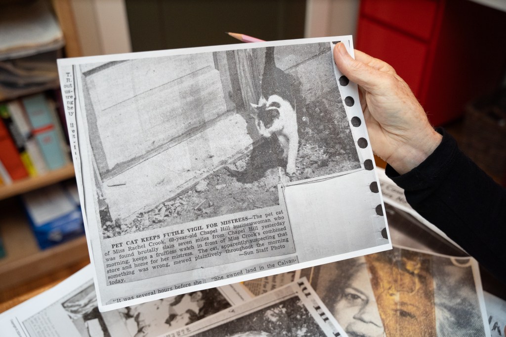 Elizabeth Woodman poses for a portrait with a newspaper archive about the 1951 murder of Rachel Crookand her pet cat. Woodman referenced archival materials to produce a four-episode podcast series about Crook and the circumstances of her murder case, in which a suspect was never convicted. Photo by Angelica Edwards.