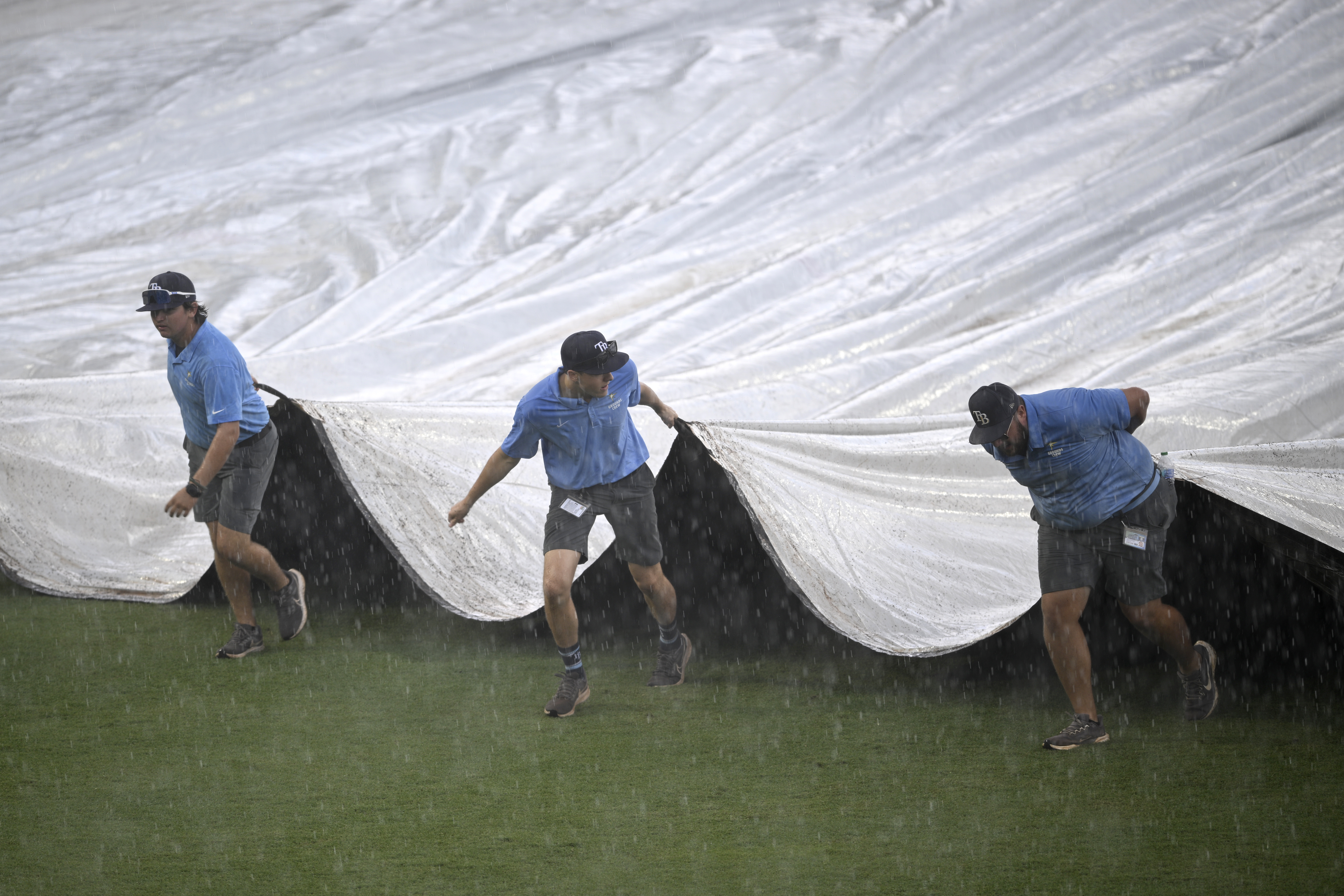 Members of the grounds crew cover the infield during a...