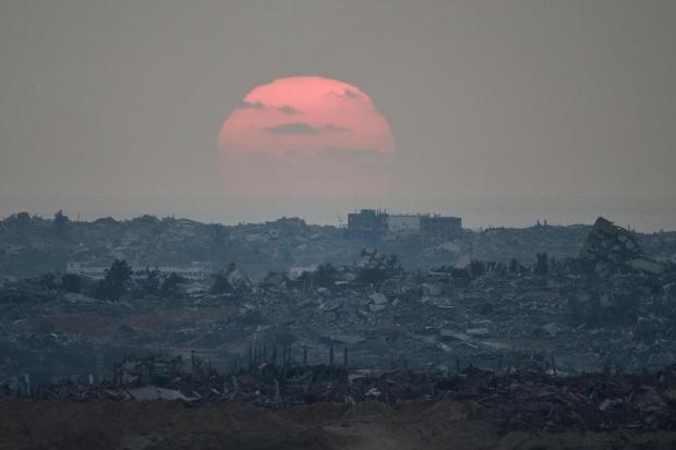 The sun sets behind buildings that were destroyed during the Israeli ground and air operations