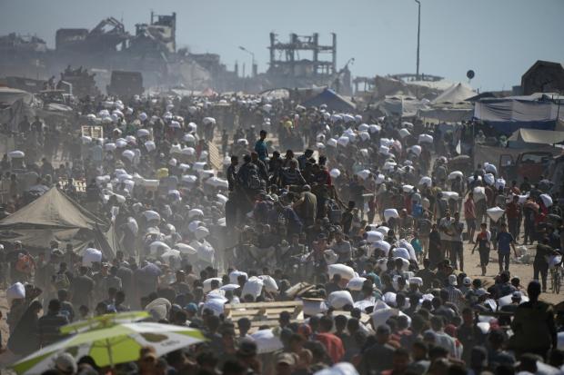 FILE – Palestinians carry sacks of flour taken from a...