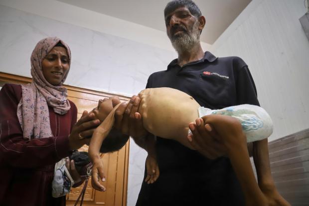 Islam Al-Najjar caresses the body of her 5-year-old nephew, Jamal...