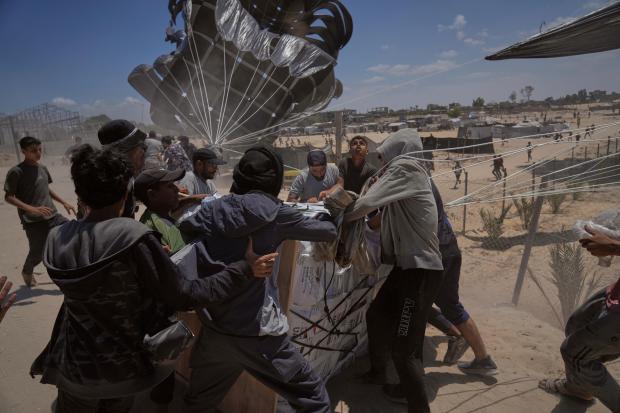 FILE – Palestinians rush to collect humanitarian aid airdropped by...