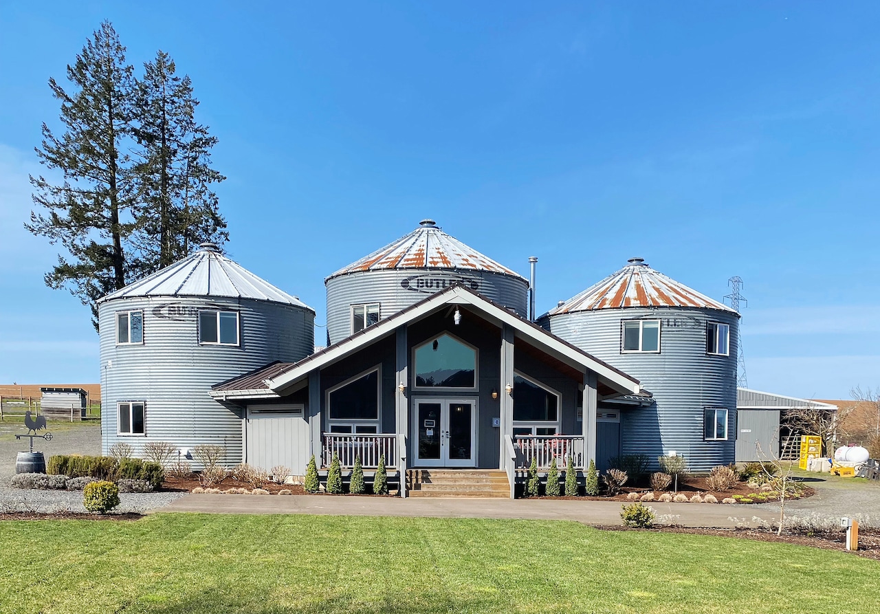 The exterior of building. Three grain silos stand beside each other connected by what looks like a little house.