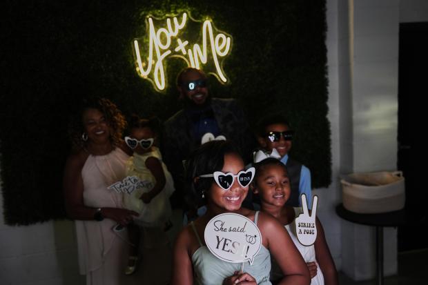 Bridesmaid Dakota-Jade Jones, front center, poses in a photo booth...