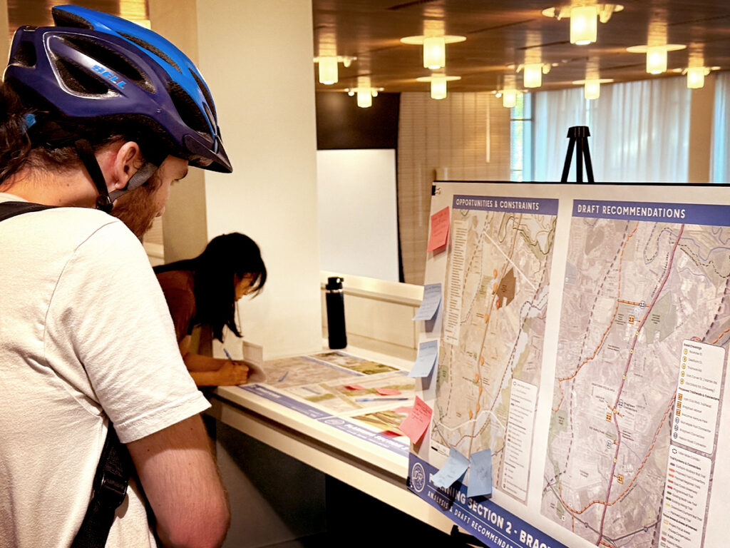 A cyclist reviews the proposed route for the Durham-to-Roxboro Rail Trail at a public engagement event in August 2025.