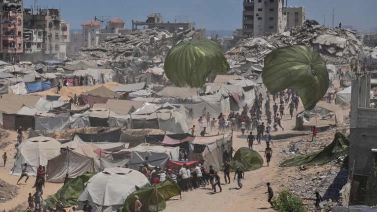 Palestinians rush to collect humanitarian aid airdropped by parachutes.