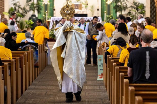 Fr. Larry Dowling processes with the Eucharist in a monstrance...