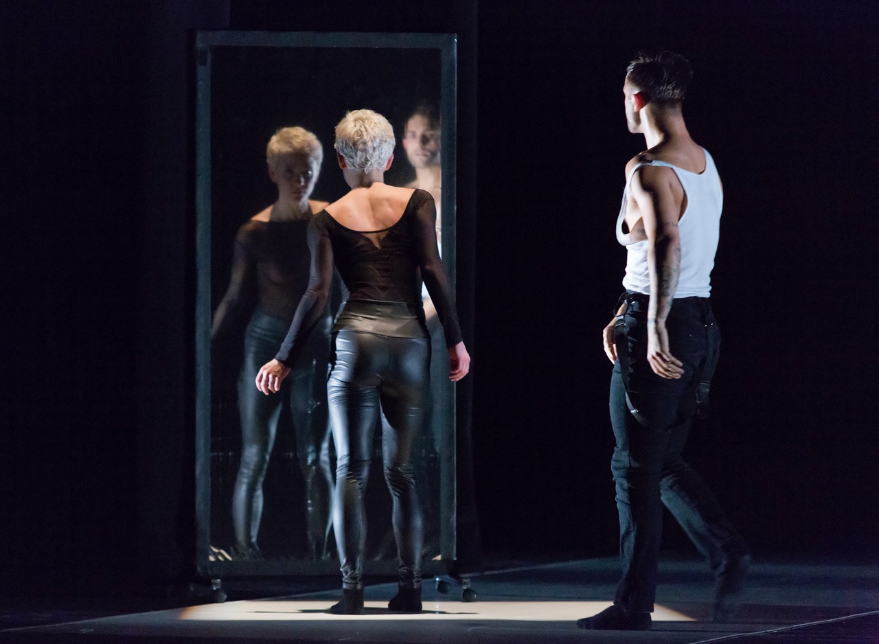 A man and a woman wearing black clothing perform a modern dance.
