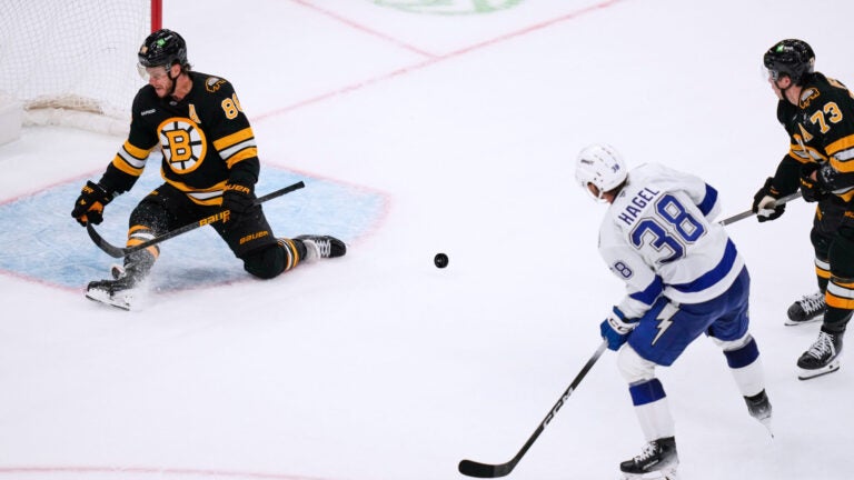 Boston Bruins right wing David Pastrnak (88) makes a save on a shot by Tampa Bay Lightning left wing Brandon Hagel (38), while protecting the empty net, during the third period of an NHL hockey game, Monday, Oct. 13, 2025, in Boston.