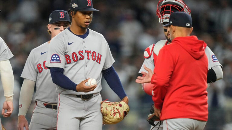 Boston Red Sox pitcher Brayan Bello hands the ball to Boston Red Sox manager Alex Cora as he leaves the game in the third inning of Game 2 of an American League wild-card baseball playoff series against the New York Yankees, Wednesday, Oct. 1, 2025, in New York.