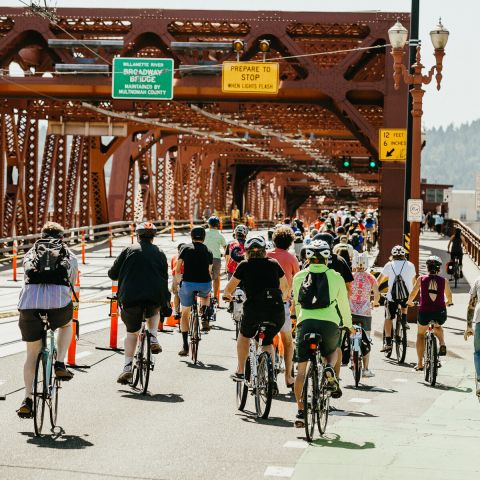 a crowd of people biking across a bridge