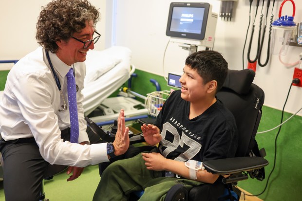 Dr. Carlos Prada high-fives Kevin Manny, of Aurora, during Manny's study visit for a clinical trial at Lurie Children's Hospital, Dec. 9, 2025. Manny was diagnosed with Duchenne muscular dystrophy when he was 7. (Eileen T. Meslar/Chicago Tribune)
