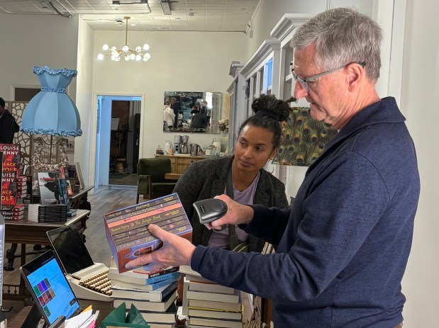Dave Larsen checks out a customer buying a set of books including "The Jungle Book" and "Treasure Island" at Beyond the Book, downtown Homewood, Dec. 18, 2025. (Evy Lewis/Daily Southtown)