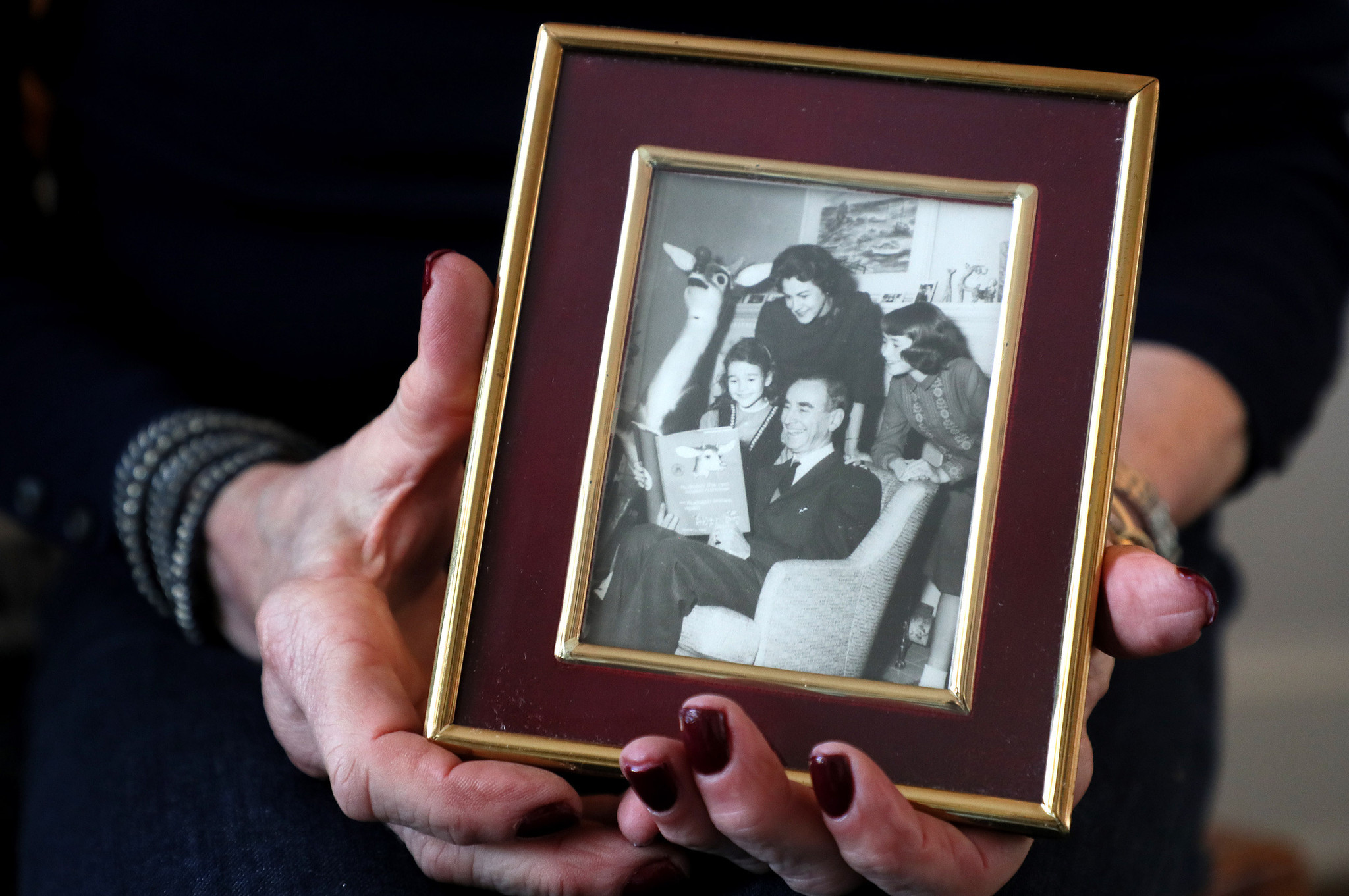 Martha May holds a photo from the 1960s of her dad, Robert; mom, Virginia; sister, Betsy; and herself.