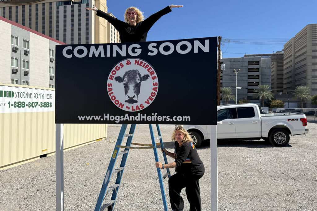 Michelle Dell (arms out) and Michelle Sandler show off the new, temporary sign just installed a ...