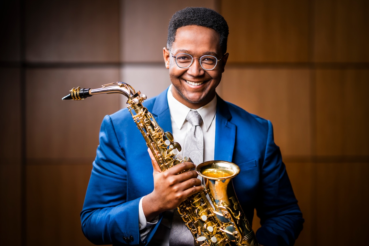 Steven Banks smiles as he poses with a saxophone