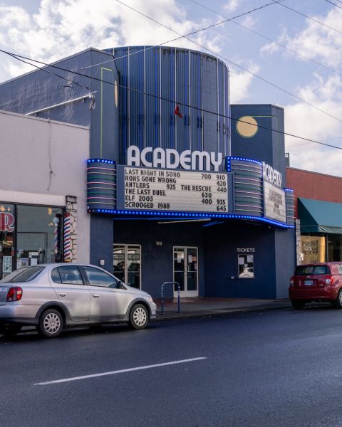 a blue theater with a car parked out front