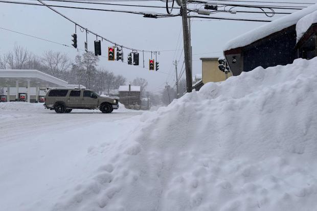 Traffic passes piled-up snow in Lowville, N.Y., Tuesday, Jan. 20, 2026. (AP Photo/Cara Anna)