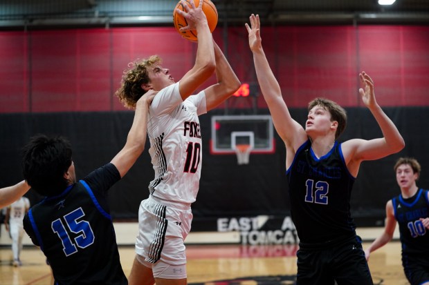 Yorkville's Graham Martinson (10) powers to the basket against St. Charles North's Ansh Salwan (15) and Jacob Love (12) during a Ernie Kivisto Hoops Fest game in Aurora on Saturday, Jan. 31, 2026. (Sean King / For The Beacon-News)
