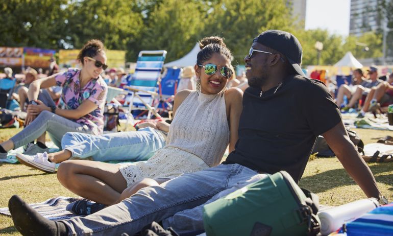 two people sit together in the sunshine in the middle of a crowd