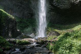 a waterfall dropping from a rock cliff into a stream below