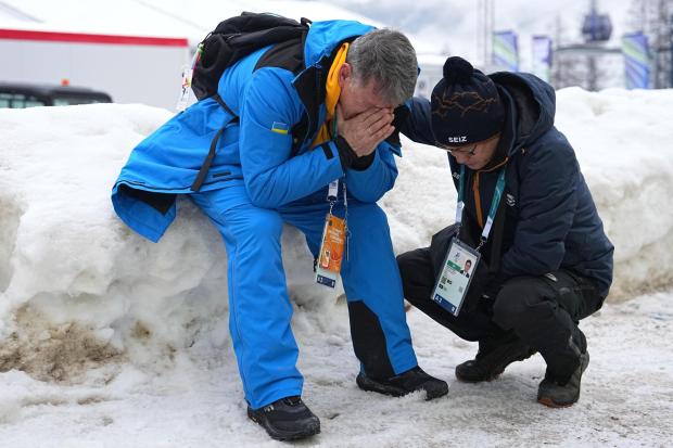 Mykhailo Heraskevych, father of Ukrainian skeleton athlete Vladyslav Heraskevych, reacts as he sits next to the start house of the sliding center at the 2026 Winter Olympics, in Cortina 