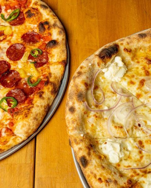 two pizzas cut into large slices with various toppings