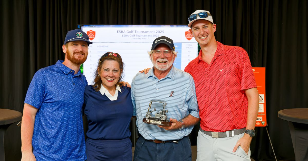four people standing with a trophy
