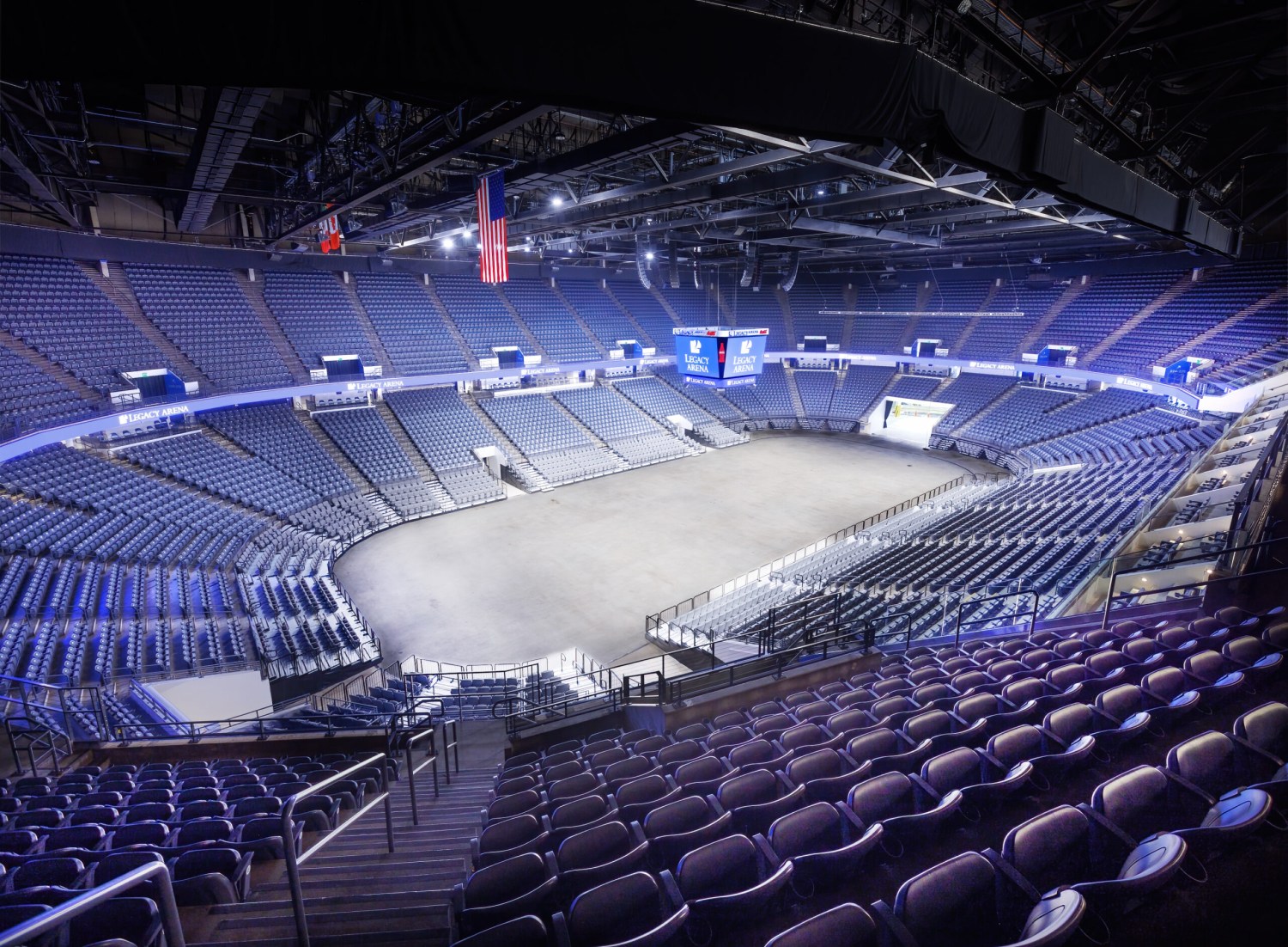 Interior view of Legacy Arena showing the empty seating bowl, center-hung scoreboard, and open floor from an upper-level vantage point