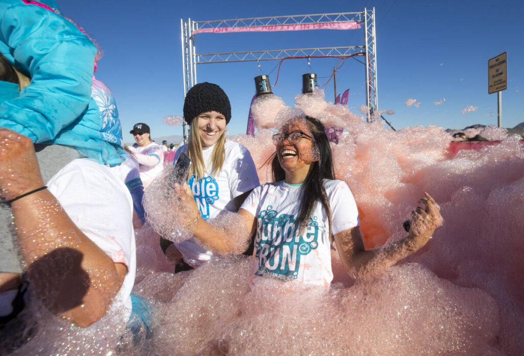 Brittany Stuckey, left, and Annegenelle Figueroa emerge from the colored foam as they take part ...