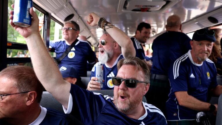 Members of the Tartan Army sing and cheer during a school bus ride to Foxborough for Scotland’s World Cup match.