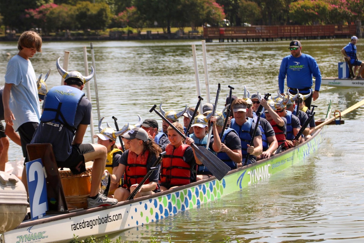A team wearing Viking helmets and life jackets paddles a dragon boat on East Lake Park during the Mitchell's Place Dragon Boat Race Festival