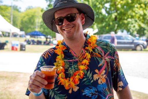 Man in a tropical shirt and lei holding a cocktail at the Dragon Boat Festival cocktail contest