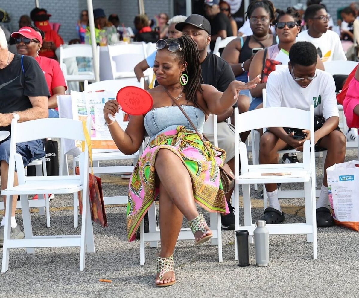 FREE I Love Irondale Day 2026 brings food, fun + tech 6 A woman in a colorful dashiki skirt fans herself while dancing among a crowd of attendees seated in white folding chairs at I Love Irondale Day